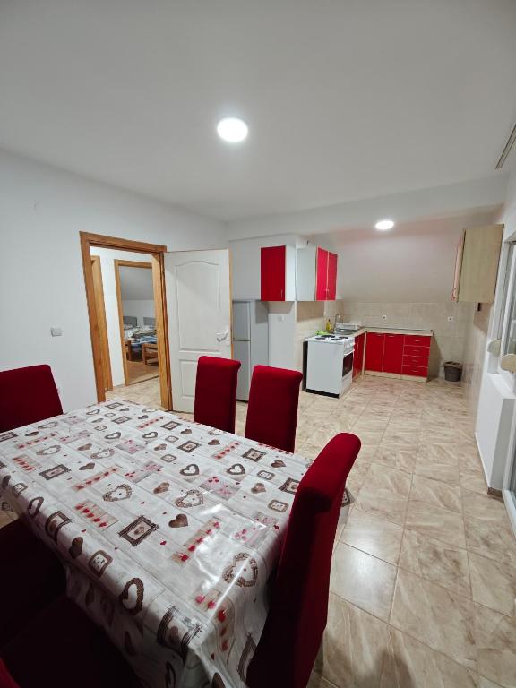 a dining room table with red chairs and a kitchen at Čiča 1 in Dobanovci