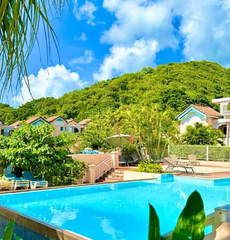 a resort swimming pool with a mountain in the background at Chez Ti Julio - Appartment Premium in Sainte-Anne