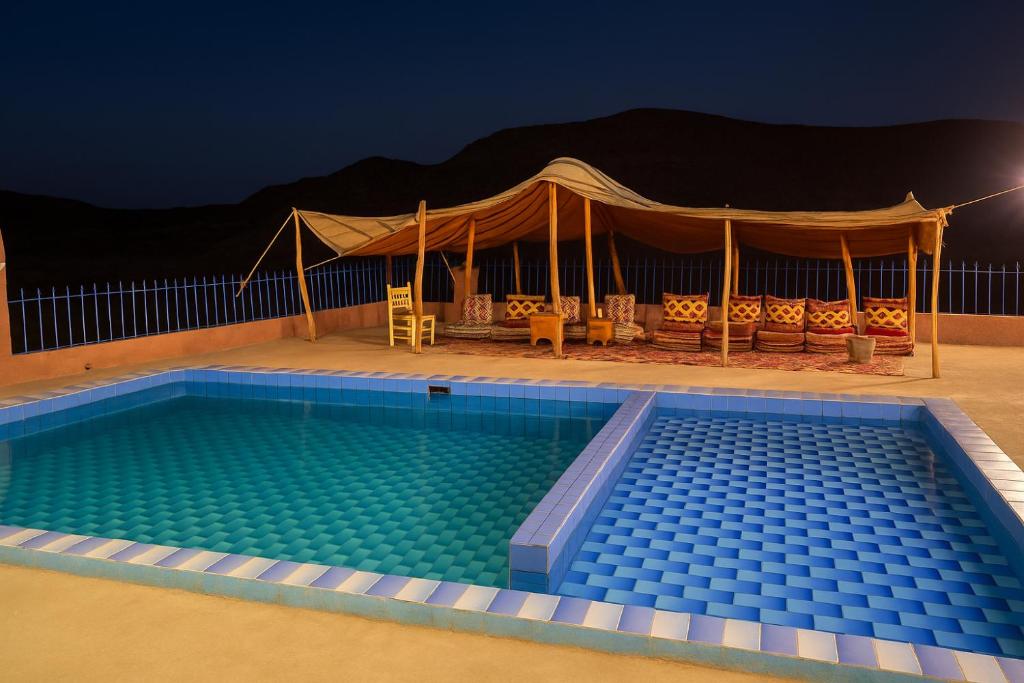 una piscina por la noche con una tienda en Grotte Salwa, en Aït Ben Haddou