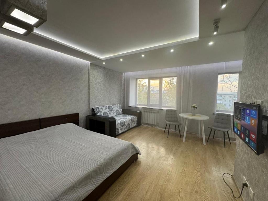 een slaapkamer met een bed, een bank en een tafel bij Квартира in Karagandy