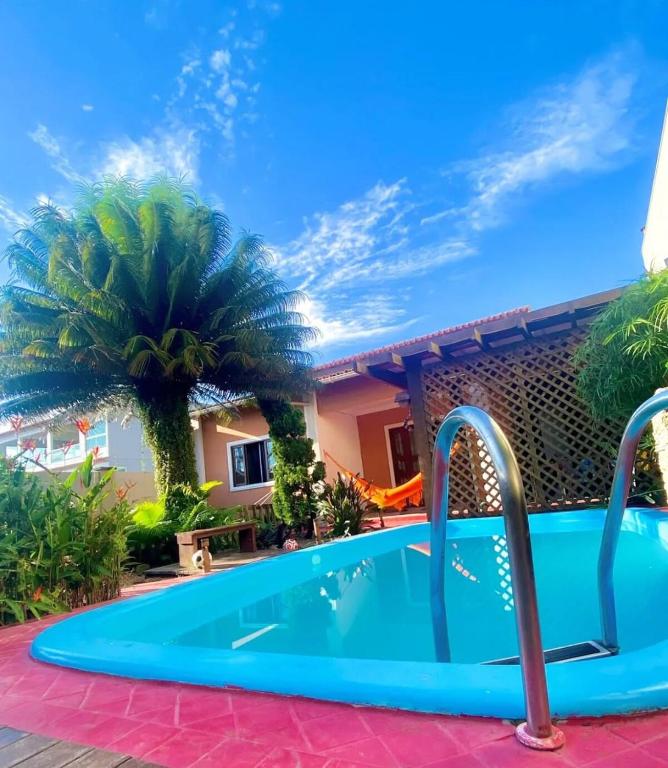 a swimming pool in front of a house with a palm tree at Sossego Ponta da Fruta in Vila Velha