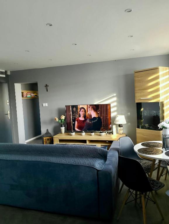 een woonkamer met een blauwe bank en een tv aan de muur bij Apartment Manhattan in Tarnowskie Góry