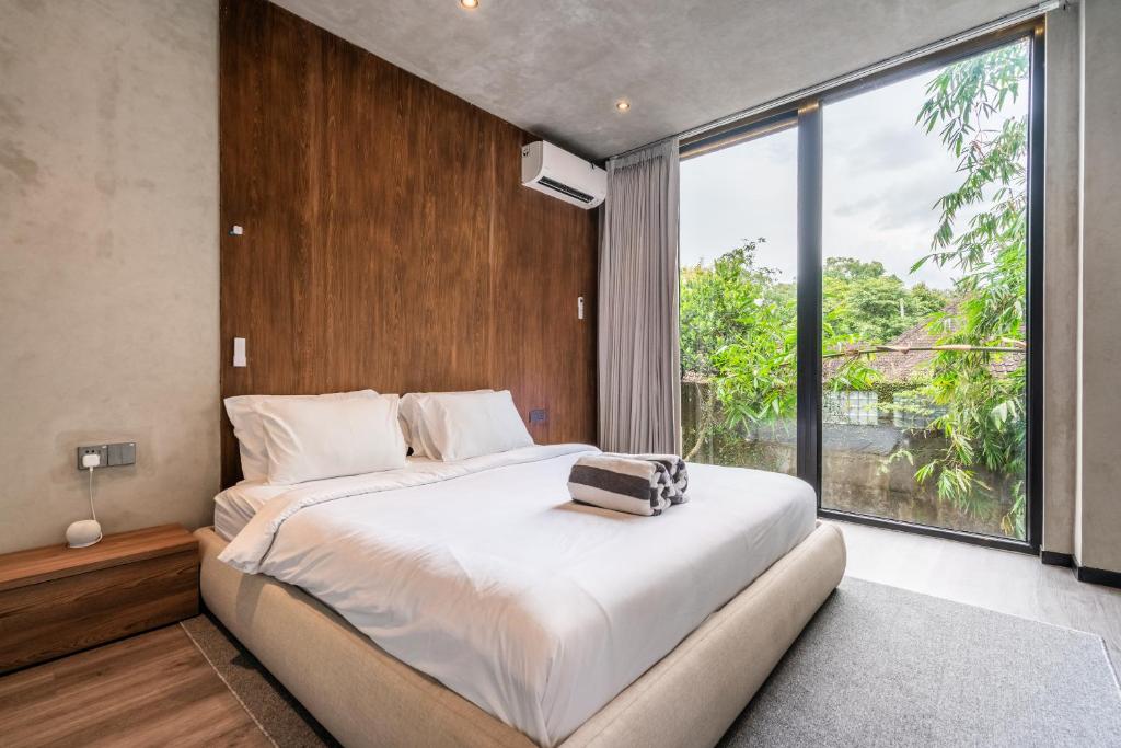 ein Schlafzimmer mit einem großen Bett und einem großen Fenster in der Unterkunft MODERN AND COMFORTABLE JUNGLE VISTA HOTEL Ubud Bali By JV with a relaxing atmosphere in Ubud