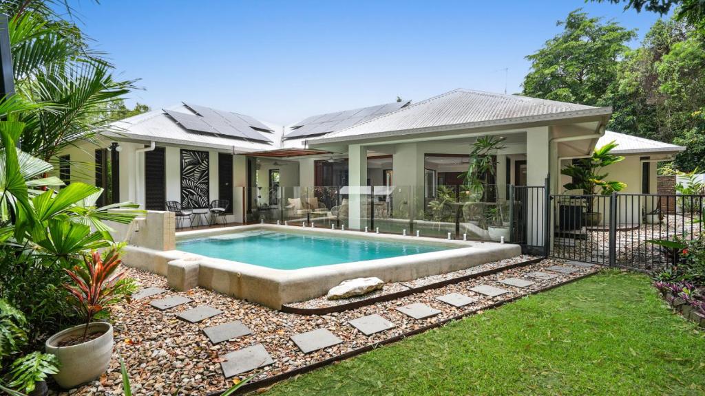 een huis met een zwembad in de tuin bij Shambala at Palm Cove in Palm Beach