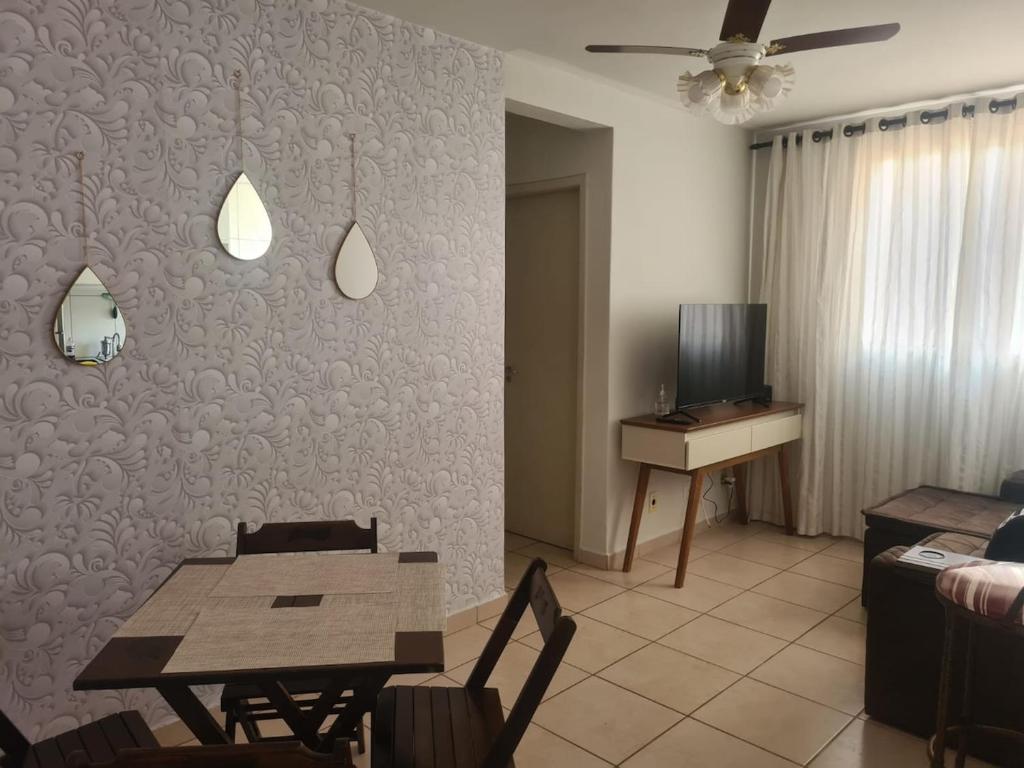 a living room with a table and a television at Belo Apto ao lado do Shopping in Franca