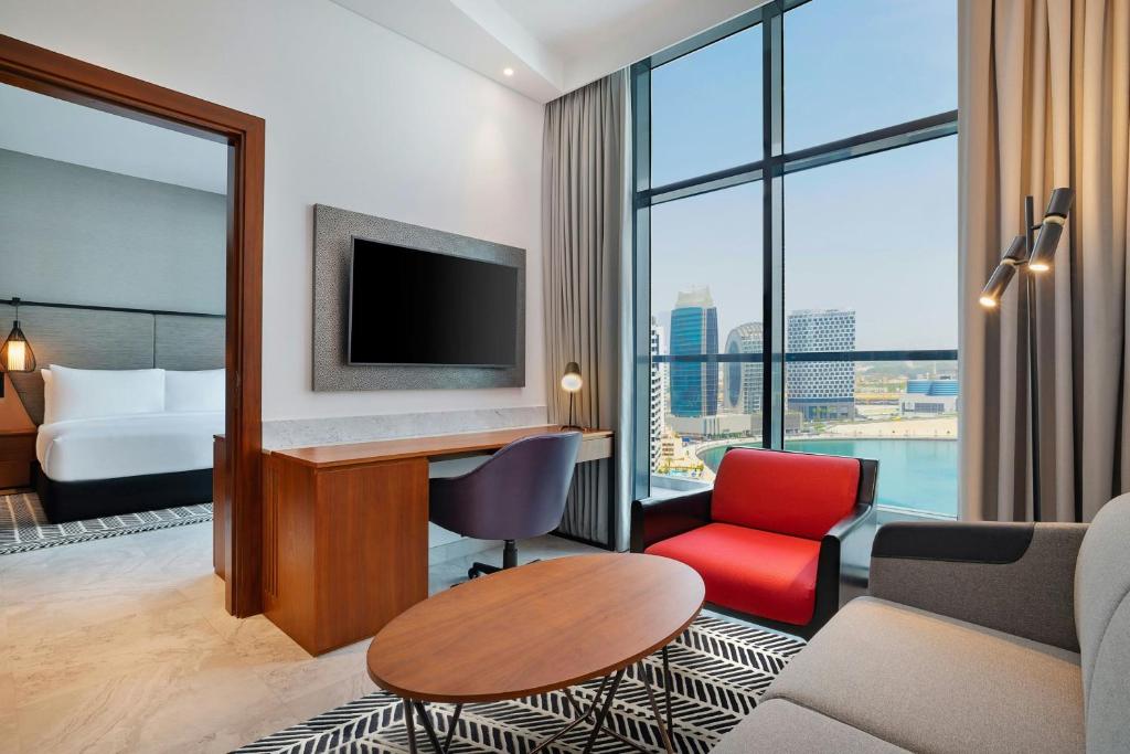 a hotel room with a couch and a desk with a tv at The First Collection Waterfront, Dubai, a Tribute Portfolio Hotel in Dubai