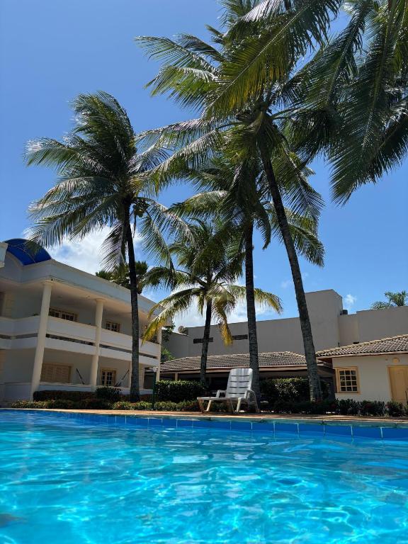 a pool in front of a hotel with palm trees at Villa das Araras Residence in Porto Seguro