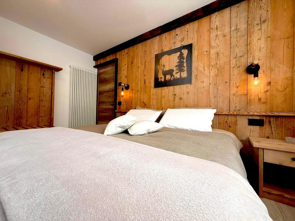 a bedroom with a large bed with wooden walls at Nos Sweet Home in Dimaro