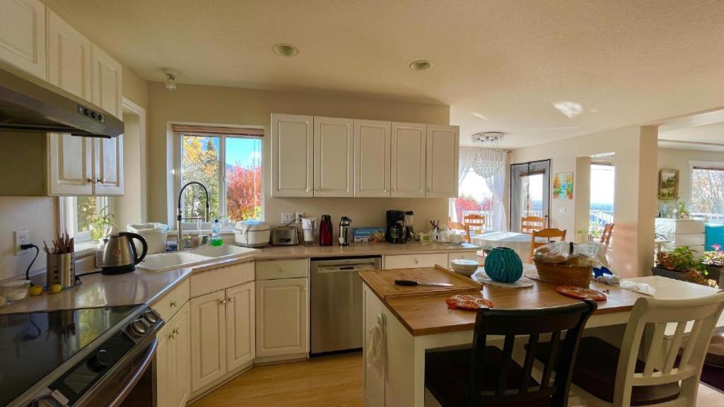 una cucina con mobili bianchi e un tavolo con sedie di warm house2 a Coquitlam