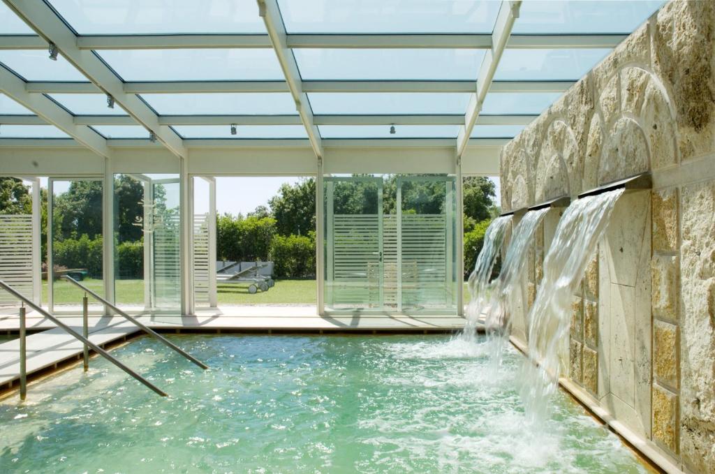 a swimming pool with a waterfall in the middle of it at Albergo Le Terme in Bagno Vignoni