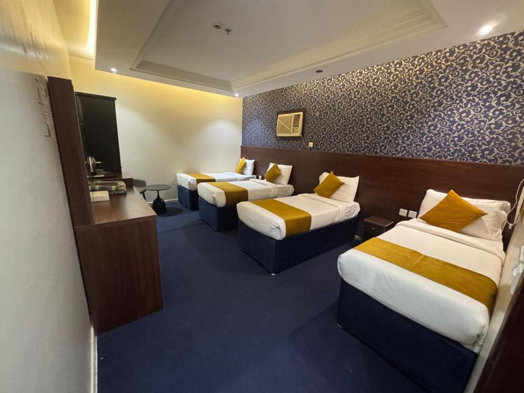 a hotel room with three beds and a flat screen tv at فندق ملتقى الايمان للضيافة السياحي in Al ‘Azīzīyah