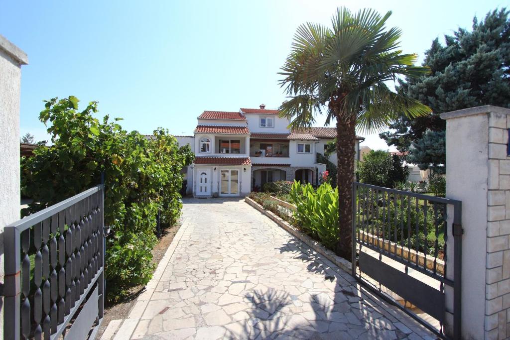 a white house with a palm tree and a driveway at Apartment Neily in Rovinj