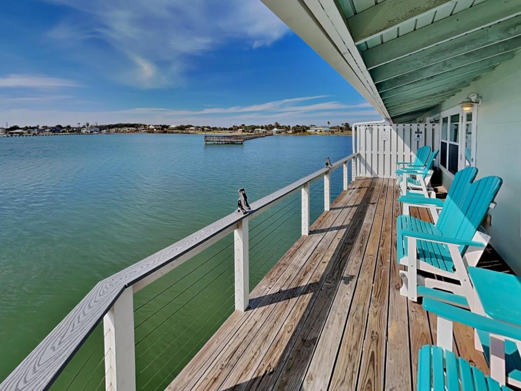 Un porche con sillas azules y el agua. en Pelican B Reef, en Rockport