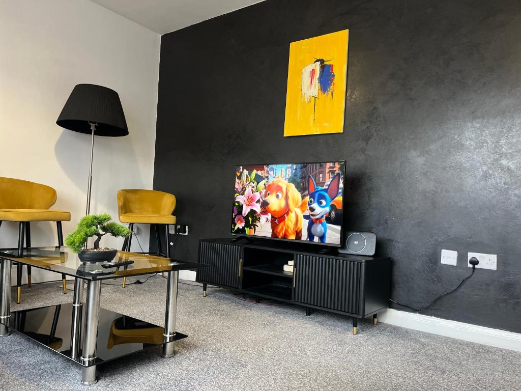 un soggiorno con TV a schermo piatto su una parete nera di Just Stay 2 a Warrington