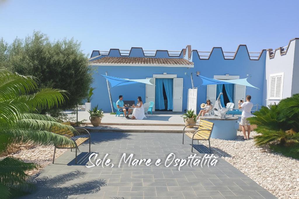 een groep mensen die buiten een blauw huis zitten bij Villa del Marinaio in Mazara del Vallo