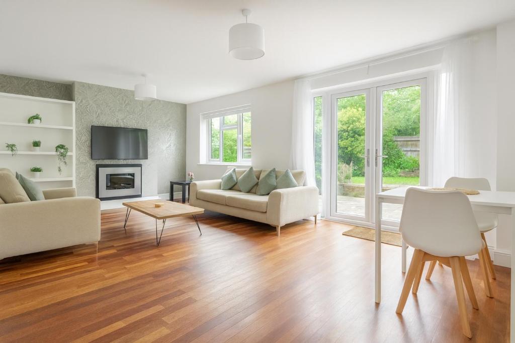 a living room with white furniture and wood floors at 4 Bed House, MK Centre with Parking Contractor & Family Friendly in Haversham