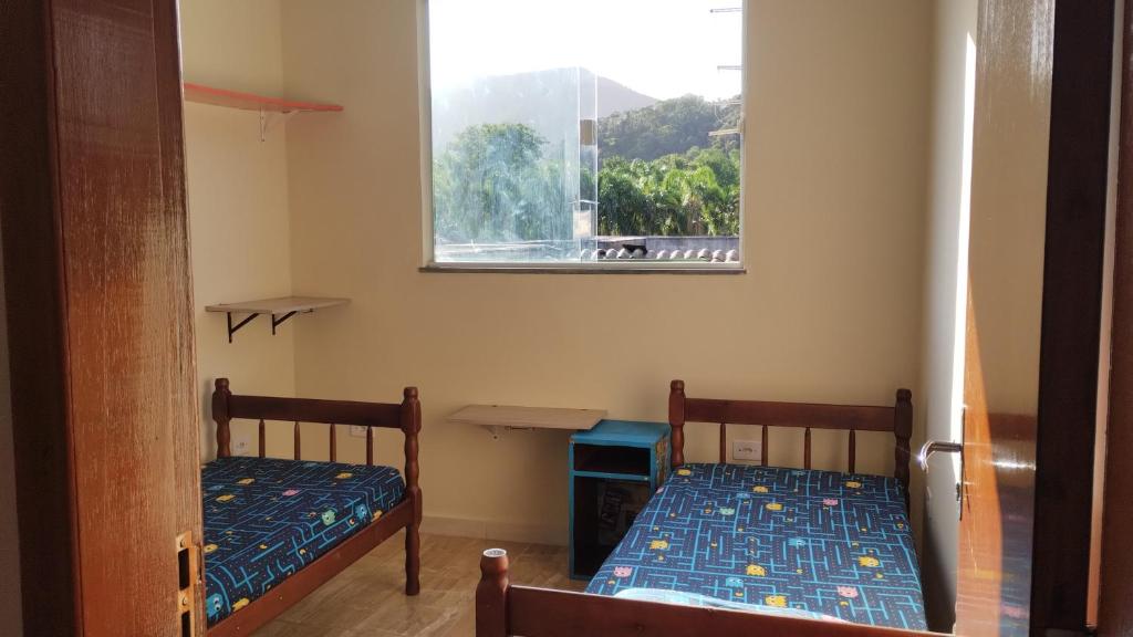 two beds in a room with a window at Quarto do Sol Relaxante - 150m da praia in Ubatuba