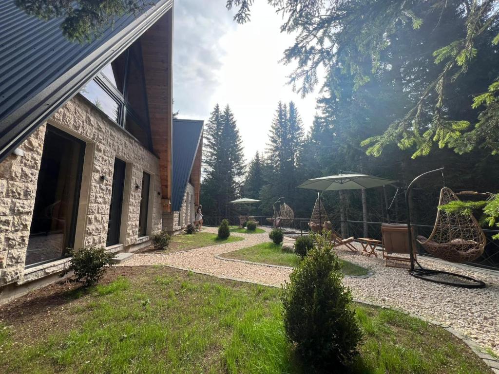 un patio con sombrilla junto a un edificio en Green Hideaway SPA, en Žabljak