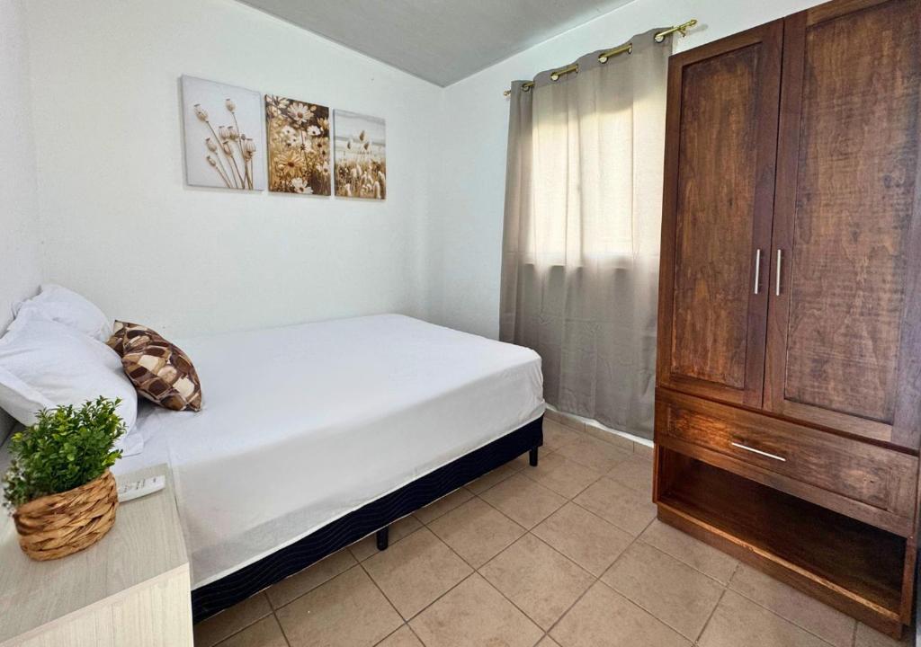 une chambre avec un lit blanc et une armoire en bois dans l'établissement Colibri de Montaña, à Ahuachapán