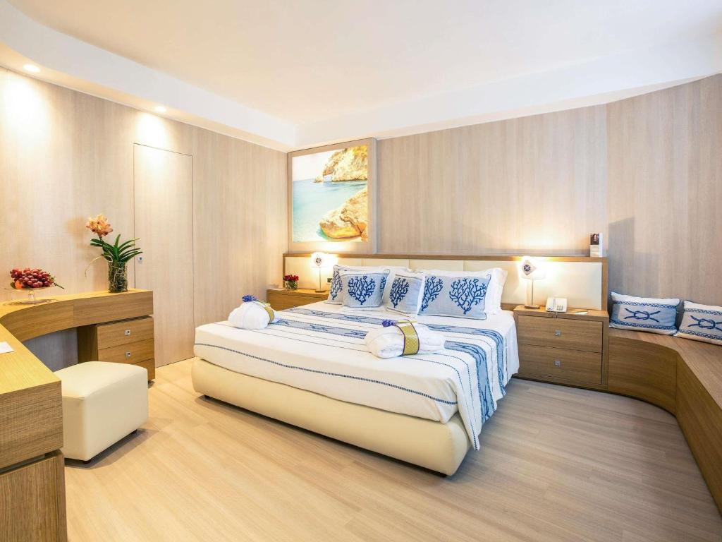 ein Schlafzimmer mit einem großen Bett mit blauen Kissen in der Unterkunft Mercure Olbia in Olbia
