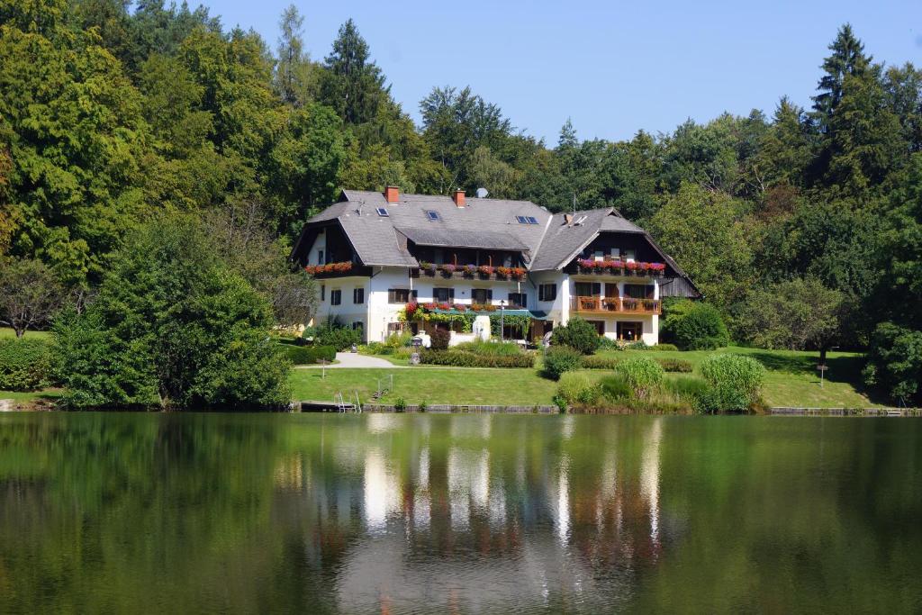 uma casa numa colina ao lado de um lago em Landgasthof Trattnig em Schiefling am See