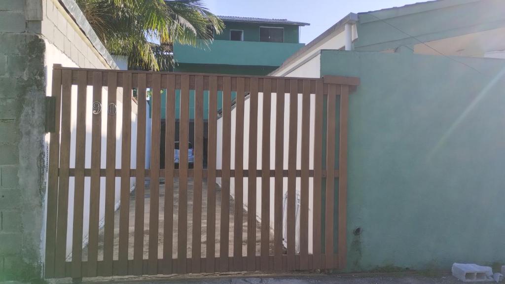 a wooden gate in front of a white wall at Casa do Sol, Pássaros e Montanhas em Ubatuba Barra Seca in Ubatuba