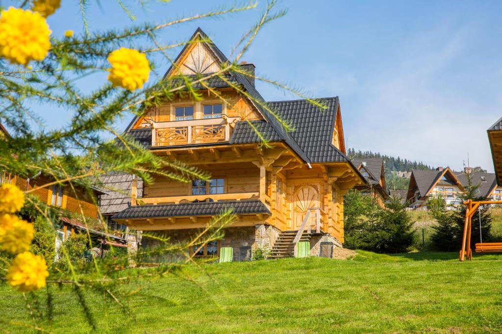 een groot houten huis met een groene tuin bij udanypobyt Dom Bright House in Kościelisko