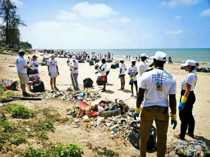 Un grupo de personas de pie alrededor de una pila de basura en una playa. en Guide local tourismeco saly, en Sali Poulang