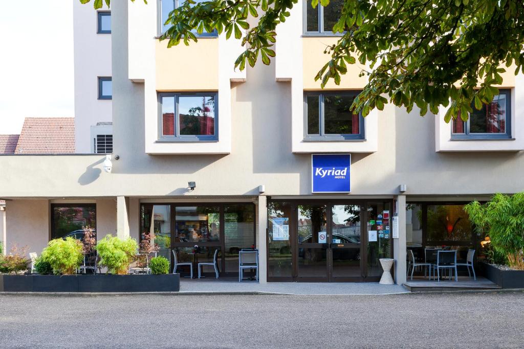 a building with tables and chairs inside of it at Kyriad Hotel Strasbourg Lingolsheim in Lingolsheim