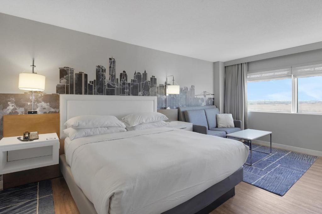 a bedroom with a large white bed and a city at World of Blue 711 I Beautiful King Hotel Room in Secaucus