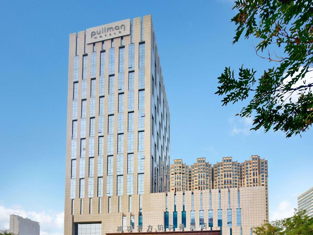 a tall building with a sign on top of it at Pullman Weifang in Weifang