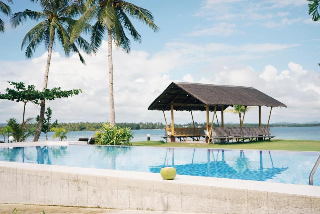 a swimming pool with a gazebo and palm trees at Ocean 101 Beach Resort in General Luna