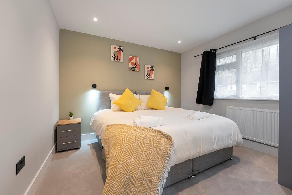 een slaapkamer met een bed met gele kussens en een raam bij Modern High Spec Home in Titsey