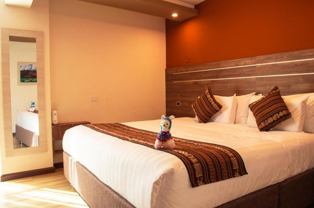 un perro pequeño sentado en una cama en un dormitorio en INKALAM cusco, en Cusco