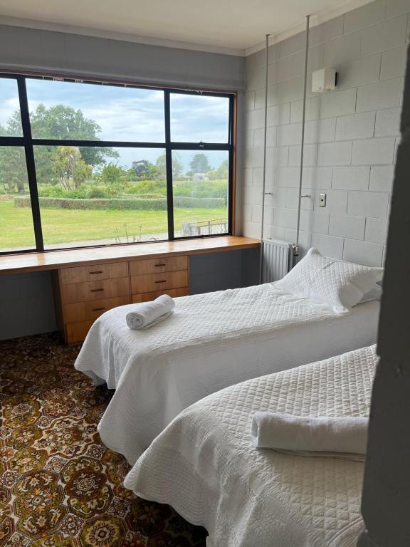 two beds in a room with a large window at Quiet country setting- R3 Magnolia House in Temuka