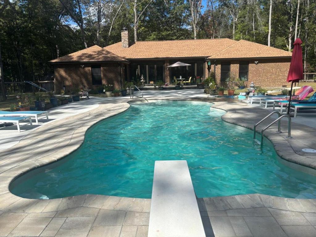 a swimming pool with blue water in front of a house at Quiet Forest Vacation home on a Private Road with Spacious Patios, Fire pit, Pet friendly and a Private pool in Tullahoma