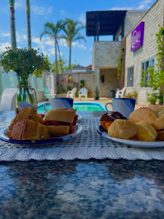 two plates of sandwiches on a table next to a pool at Suíte Maresia - Pousada Castelo do Luar in Penha