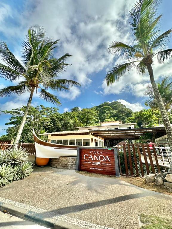 a boat parked in front of a building with palm trees at Pousada Casa Canoa - Pé na Areia & Alta Gastronomia in Guarujá