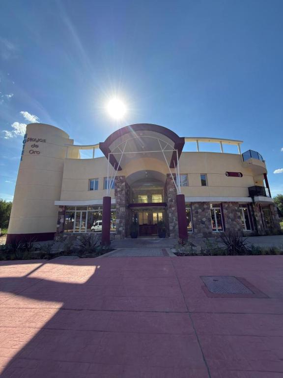 a large building with the sun shining behind it at Hotel Playas De Oro in Villa Carlos Paz