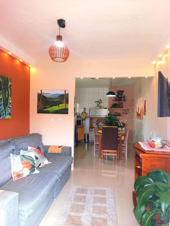 a living room with a couch and a kitchen at Casa temporada perto do centro in Garopaba