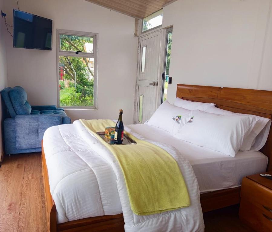 Un dormitorio con una cama con una botella de vino. en Cabaña Colibrí Silvania Cundinamarca, en Silvania