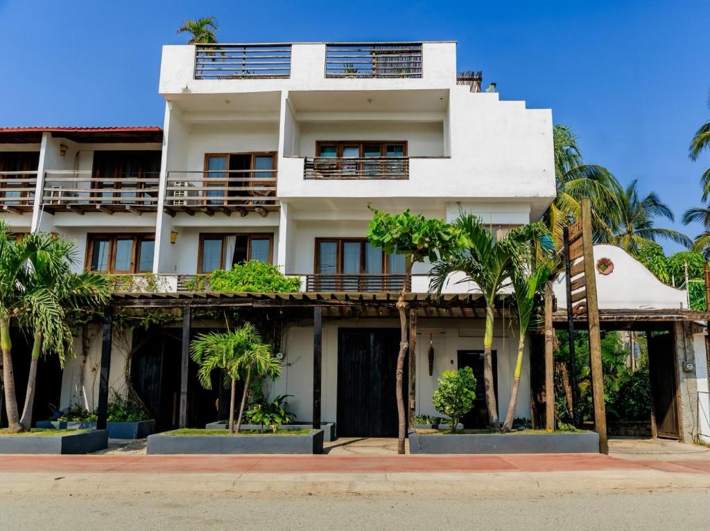 a white building with palm trees in front of it at Hotel Verdemar in Acapulco