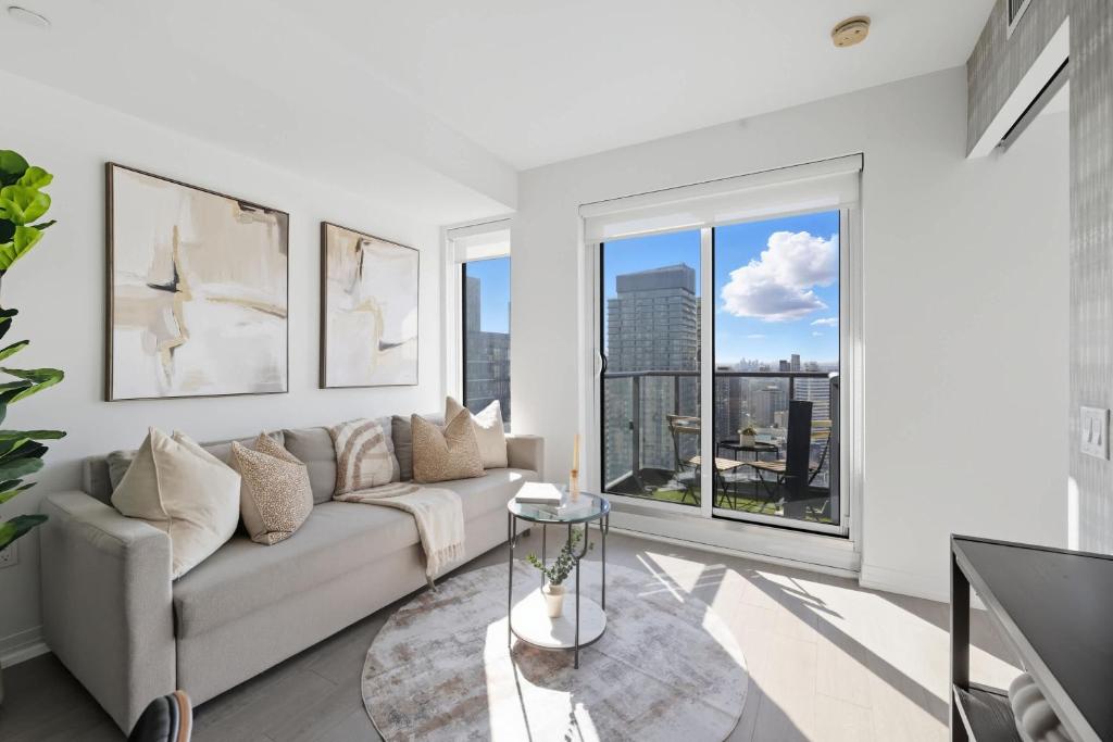 a living room with a couch and a large window at Toronto Skyline Stay Modern Design & View in Toronto