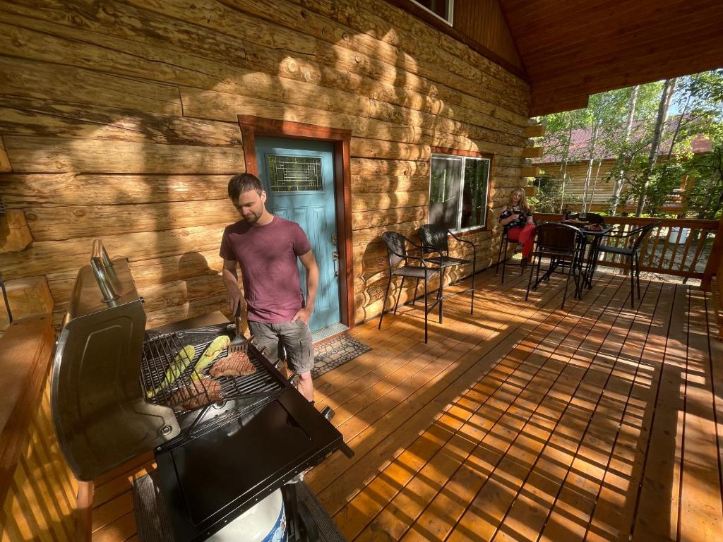 a man standing on a screened in porch at Riverfront, Authentic, Luxury Log Cabin-Black Bear in Wasilla