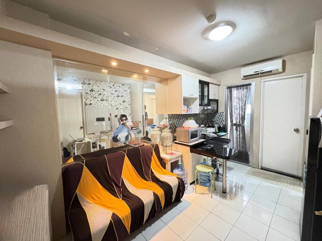 雅加达Cozy 2BR Kalibata City的房间里，厨房里有个操作台，旁边是一个人。