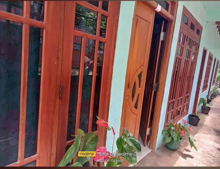 an entrance to a house with wooden doors and flowers at Uva Guest Udawewa in Diyatalawa