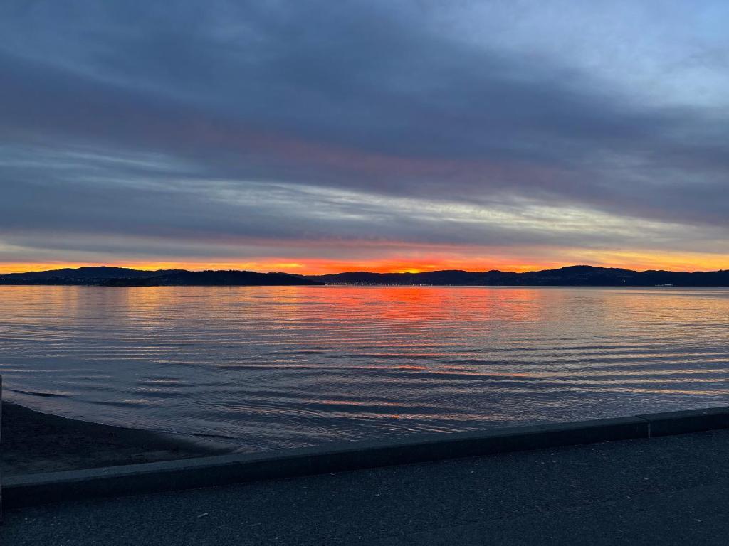 a large body of water with a sunset in the background at Unique Beachside Home in Eastbourne in Lower Hutt