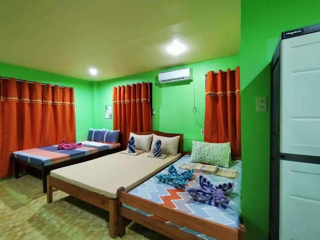 a living room with two beds and green walls at Charming Urban Hideout in Puerto Princesa City