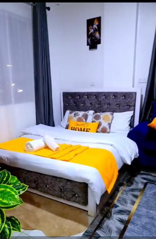 a bedroom with a bed with yellow and white sheets at Naivera Membley star heights in Ruiru