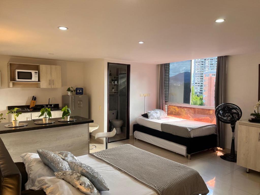 1 dormitorio con 1 cama y cocina con ventana en Poblado ApartaSuite familiar cerca club campestre, en Medellín